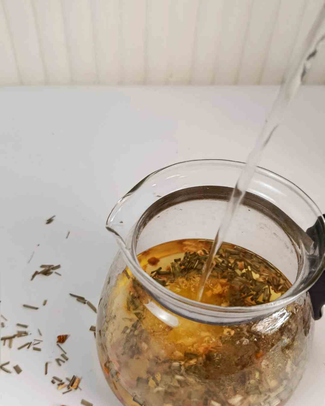 Priprava zeliščnega čaja iz uva ursi z vročo vodo v steklenem čajniku